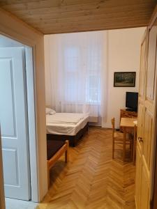 セゲドにあるOKSZI Vendégházのベッド、デスク、窓が備わる小さな客室です。
