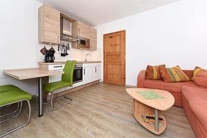 ein Wohnzimmer mit einem roten Sofa und einer Küche in der Unterkunft Pension Pradler Wohnung 2 in Carolinensiel