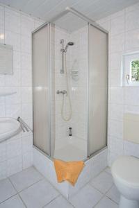 ein weißes Badezimmer mit Dusche und Toilette in der Unterkunft Pension Pradler Wohnung 2 in Carolinensiel + 4 Fotos