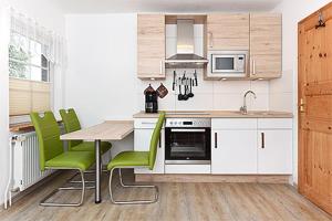 eine Küche mit einem Tisch und grünen Stühlen darin in der Unterkunft Pension Pradler Wohnung 2 in Carolinensiel