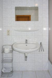 ein weißes Badezimmer mit Waschbecken und Spiegel in der Unterkunft Pension Pradler Wohnung 2 in Carolinensiel
