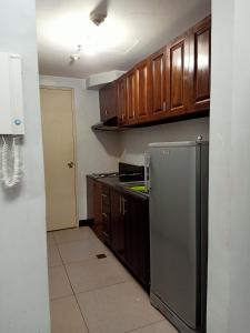 a kitchen with wooden cabinets and a stainless steel refrigerator at Taj's Condotel in Manila