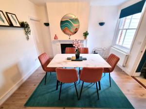 a dining room with a table and chairs and a fireplace at Beautiful & Vibrant City Centre House in Canterbury