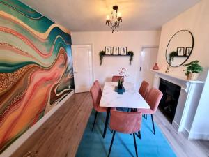 a dining room with a table and chairs and a colorful wall at Beautiful & Vibrant City Centre House in Canterbury