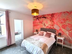 a bedroom with a bed with a red wall at Beautiful & Vibrant City Centre House in Canterbury