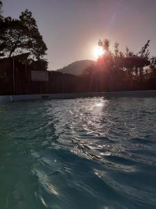 a swimming pool with the sun setting in the background at Hotel Bela Onda in Bombinhas