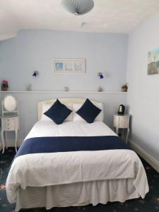 a bedroom with a large bed with blue pillows at Athol Park Guest House in Port Erin