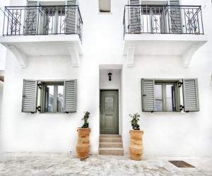 a white building with a green door and two balconies at ANGONI SUITES in Kardamaina
