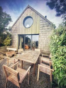 - une table de pique-nique et des chaises en face d'un bâtiment dans l'établissement Dernier Ecolodge avant NewYork, à Plogoff