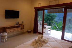 a bedroom with a bed with a television and a balcony at Abian Dauh Sidemen in Karangasem