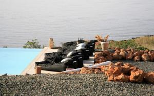 Aloe Mare Suites في Liaropá: مجموعة من الكراسي جالسين على رصيف بجانب الماء