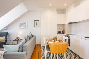 eine Küche und ein Wohnzimmer mit einem Tisch und einem Sofa in der Unterkunft Bright Tailor Made Flat With a View in Estrela in Lissabon
