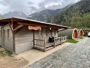 a large wooden cabin with a porch and a tent at Bungalow Miralago in Camping Cavresc, Via dal Cavresc 1, 7746 Le Prese-Poschiavo in Poschiavo
