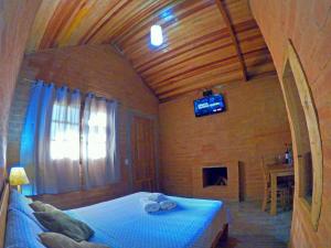 um quarto com uma cama e uma televisão num quarto em Pousada Lua Bonita em São Bento do Sapucaí