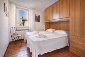 阿尔比萨诺Casa Delle Stelle的一间卧室设有两张床、一把椅子和一个窗户。