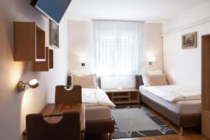 a small room with two beds and a desk and a table at Rooms Gašper in Postojna