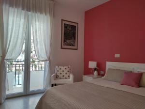 Schlafzimmer mit roten Wänden, einem Bett und einem Fenster in der Unterkunft Dimora Francesca in Conversano