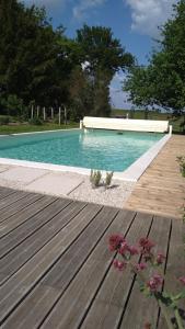 une piscine bleue avec une terrasse en bois et des fleurs dans l'établissement Longère du sud Touraine au Coeur du Val de Loire, à Saint-Jean-Saint-Germain