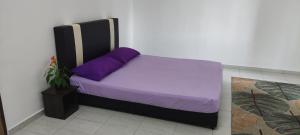 Bett in einem Zimmer mit lila und lila Kissen in der Unterkunft Afamily Homestay in Ipoh