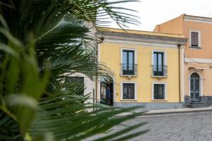 ein gelbes Gebäude auf einer Straße mit einer Palme in der Unterkunft Casa Belvedere in Piedimonte Etneo