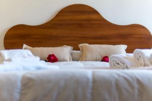 two white beds with white sheets and red roses on them at Agriturismo De Santis in Castiglioncello