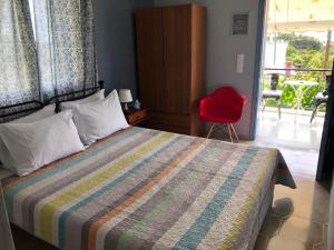sypialnia z łóżkiem i czerwonym krzesłem w obiekcie Kakovatos Studios w mieście Zacharo