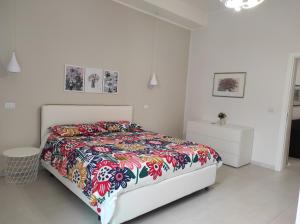 a white bedroom with a bed with a colorful bedspread at Zenzero e Limone in Catania