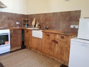 cocina con armarios de madera y nevera blanca en The Annex, Kilbride Farmhouse, en Dunoon