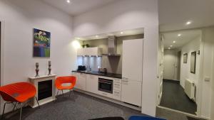 a kitchen with white cabinets and orange chairs at B&B Adrina in Zeewolde