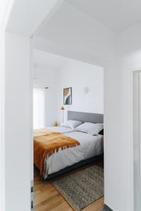 a bedroom with white walls and a bed with orange blanket at Villa Kadila with heated pool and sauna for family in Lun +25 photos