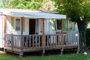 a tiny house with a porch and a white awning at Camping du Bournat in Le Bugue +24 photos