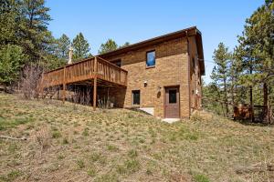 a brick house on a hill in a field at Whispering Wind in the Trees - Permit #3504 in Estes Park