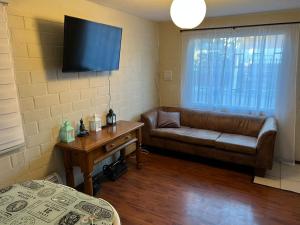 a living room with a couch and a tv on the wall at Apart Hotel Chillan - Home Cozy - Empresas - Factura - Aire acondicionado in Chillán