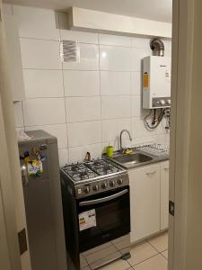 a small kitchen with a stove and a sink at Apart Hotel Chillan - Home Cozy - Empresas - Factura - Aire acondicionado in Chillán
