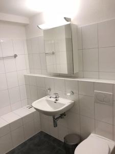 a bathroom with a sink and a toilet and a mirror at Centrally located, Spacious Modern Apartment in Zürich