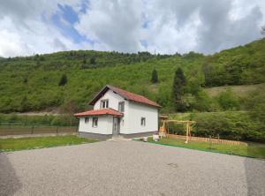 a white house with a hill in the background at Apartman Amina Vinac-Jajce in Jajce