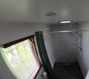 a small bathroom with a shower with a window at Strandvakantiehuisje! in Workum