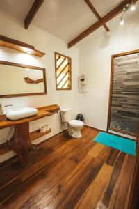 a bathroom with a toilet and a wooden floor at Passion Fruit Lodge in Cahuita