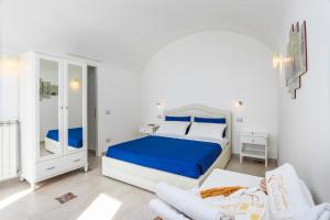 a white bedroom with a blue bed and a chair at Villa Salice in Amalfi