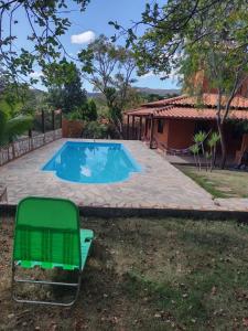 a swimming pool with a chair and a house at Pousada Mangaba da Serra in Serra do Cipo
