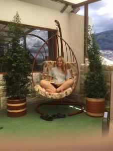 a woman sitting in a wicker chair on a porch at Hostel Revolution Quito in Quito