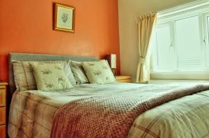 a bedroom with a bed with orange walls and a window at Haven Crest in Whitby