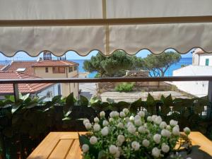 una ventana con una mesa y un jarrón de flores en IL VELIERO, en Scilla