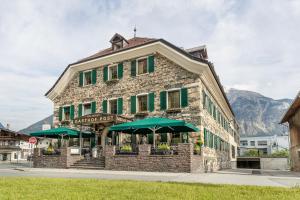 ein Gebäude mit grünen Sonnenschirmen davor in der Unterkunft Gasthof Hotel Post in Strass im Zillertal
