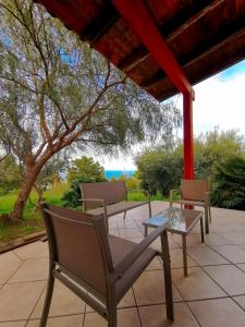 eine Terrasse mit Stühlen, einem Tisch und einem Baum in der Unterkunft L'oasi nello Zingaro in Scopello