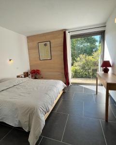 a bedroom with a bed and a desk and a window at Le Cube des Garrigues in Vallérargues