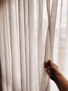 una persona está abriendo una cortina de ventana blanca en Un espacio cálido ideal para desconectar. en Buenos Aires