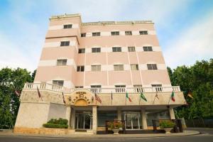 un edificio rosa con banderas delante en Hotel Los Jardines, en Santiago de los Caballeros