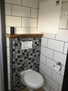 a bathroom with a white toilet and black and white tiles at Glamping aan de Thoolse kust in Poortvliet