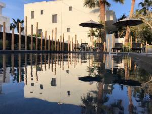 a swimming pool with chairs and umbrellas and a building at Dragonfly Villas in Kamari